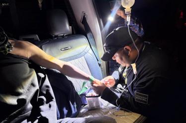 Un elemento de Proximidad Social atiende a un joven durante un traslado nocturno, mientras recibe atención médica por una picadura de alacrán.