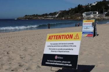 Playa de Australia Occidental con señales de advertencia y vigilancia aérea mediante drones frente a la costa, tras un ataque de tiburón.