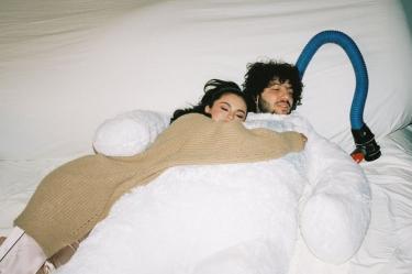 Selena Gomez abraza a Benny Blanco mientras ambos descansan juntos sobre una cama.