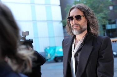 British comedian and actor Russell Brand arrives at Southwark Crown Court in south London on October 14, 2026, for the start of his trial. 51-year-old Brand faces seven sexual offence charges involving six women, relating to a period between 1999 and 2009. (Photo by Ben Stansall / AFP)