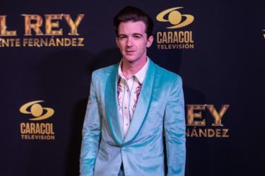 Drake Bell con traje turquesa durante un evento de El rey, Vicente Fernández, frente a un fondo de Caracol Televisión.