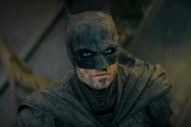 Robert Pattinson caracterizado como Batman, con máscara negra, traje oscuro y el rostro cubierto de suciedad en The Batman.