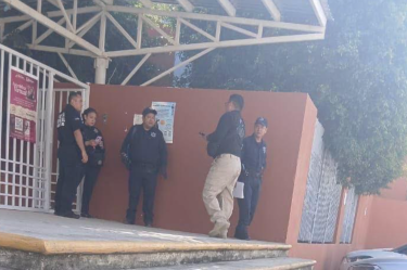 Elementos de seguridad se reúnen en el acceso de una secundaria en Querétaro, tras un reporte por la presunta presencia de un arma en el plantel educativo.
