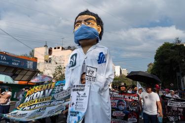 Marcha de trabajadores del IMSS y agremiados del SNTSS exigiendo un salario digno, acompañados de una figura gigante de un trabajador de la salud con cubrebocas.