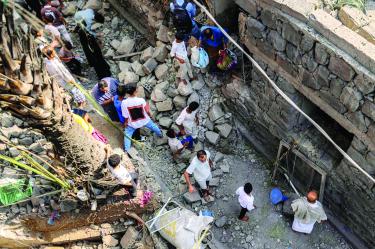 Varias personas se reúnen para buscar entre los escombros de un edificio destruido tras un presunto ataque con misiles contra un barrio residencial en Taiz.