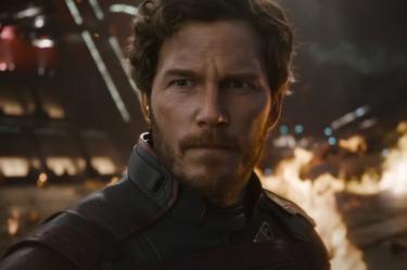 Chris Pratt como Star-Lord, con traje oscuro y expresión seria, frente a un incendio en Guardianes de la Galaxia Vol. 3.