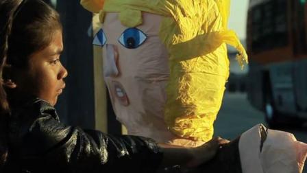 El video dirigido por Luis Aira es estelarizado por la niña hispana Sara Valesillos, quien arrastra una piñata alusiva al candidato republicano por las calles de Los Ángeles hasta tirarla en un cubo de la basura. (Tomada de YouTube)