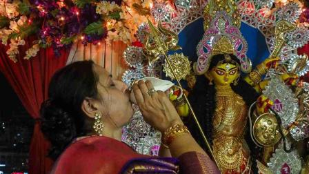 A devotee performs a ritual in front of the clay idol of Hindu goddess Durga during the ongoing Navratri and Durga Puja festival celebrations in Ahmedabad