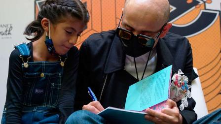 El director del ICL, Mario Méndez, firma el libro de una niña.