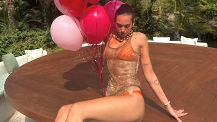 Dua Lipa con bikini naranja y blusa transparente con globos