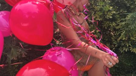 Dua Lipa con bikini naranja y blusa transparente con globos