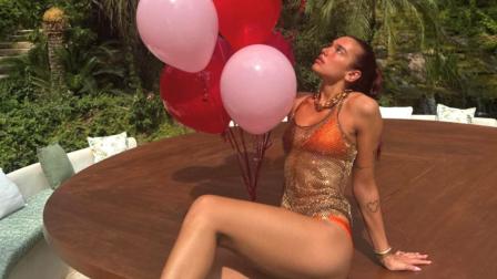 Dua Lipa con bikini naranja y blusa transparente con globos